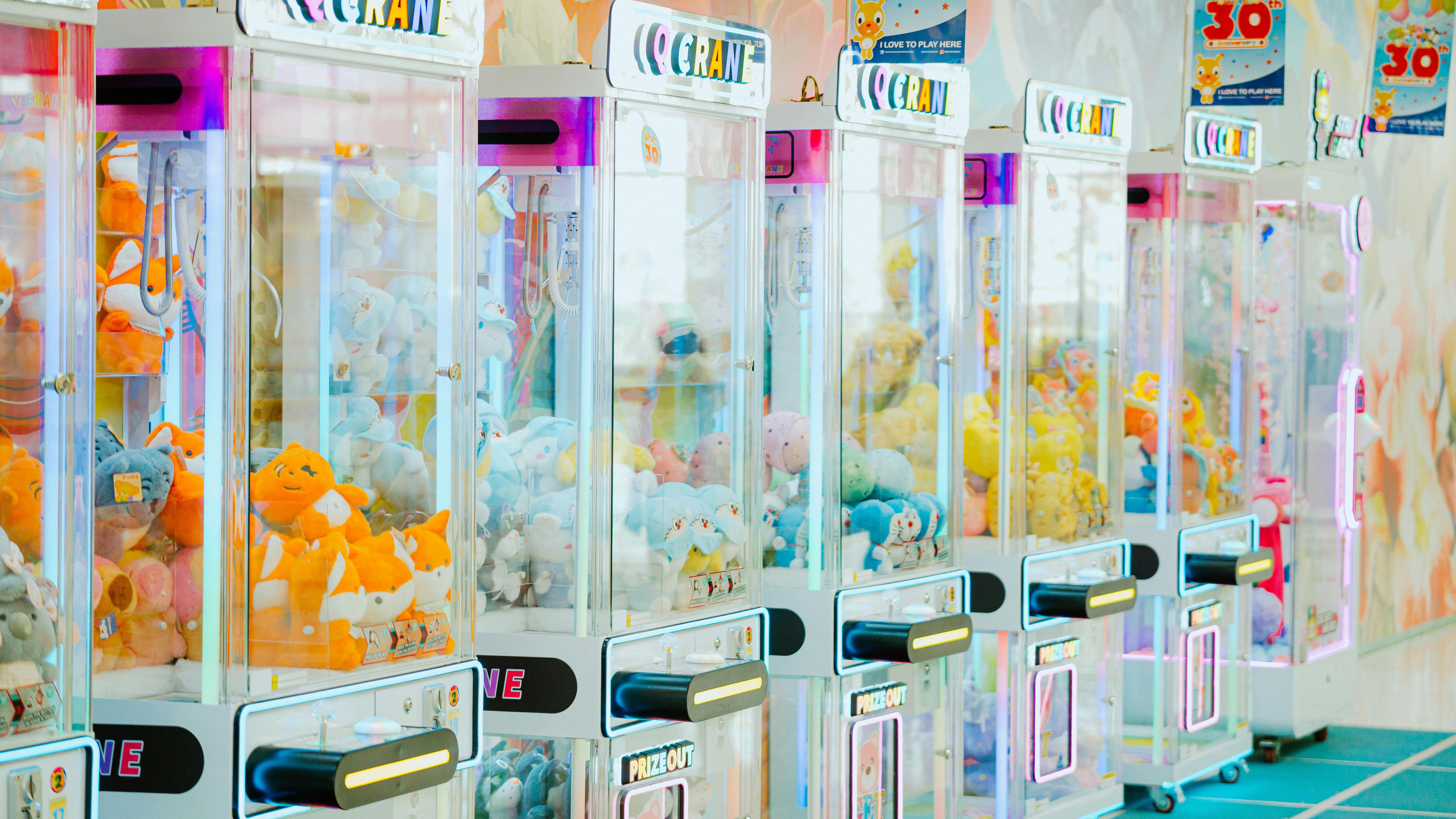 Row of colorful crane claw machines packed with plush prizes